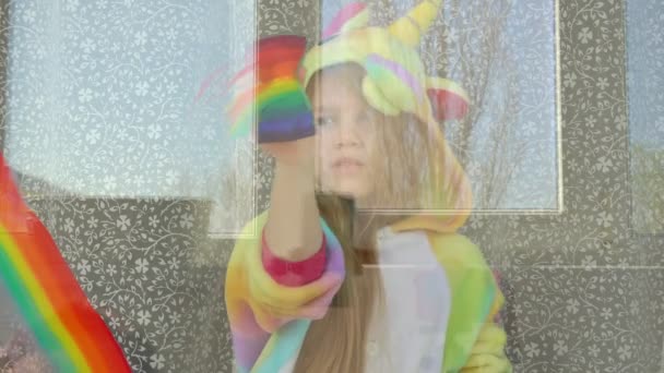 child in pajamas draws rainbow on the window. - 映像、動画