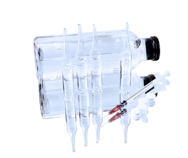 glass sealed medical ampoules with clear liquid, saline bottle, syringe and pills are reflected in a mirror surface isolated on white background - Fotografie, Obrázek