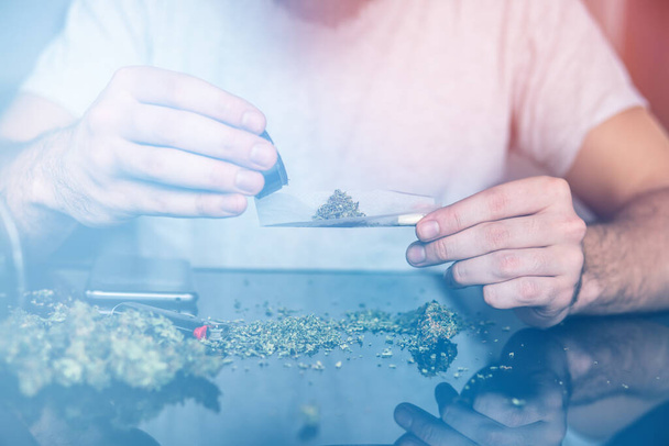 Man rolling a marijuana joint. Drug use. Man preparing and rolling marijuana cannabis joint. Close up of addict lighting up marijuana joint with lighter. Drugs narcotic concept. Close up. - Photo, Image