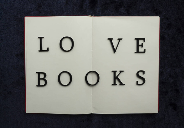 Close up to LOVE BOOKS lettering over blank notebook at blue navy background. Reading and study concept photography - Photo, Image