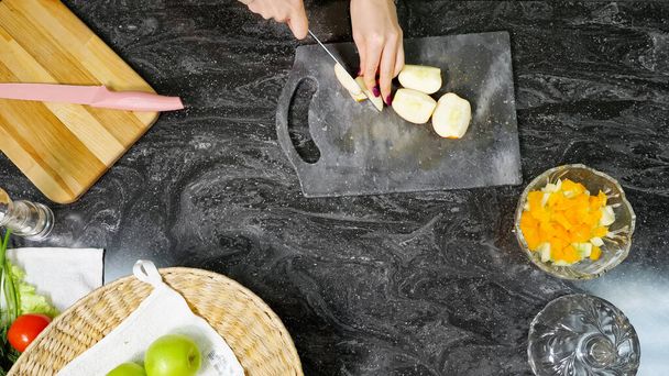 Ev hanımı mutfak masasında elma salatası kesiyor. - Fotoğraf, Görsel