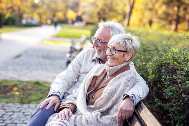 Vecchio e donna seduti sulla panchina e sorridono
 - Foto, immagini