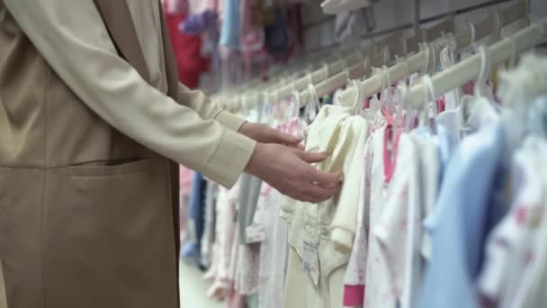 moederschap, gelukkig jong vrouw, koper kiest kleding voor kinderen, moeder in de winkel probeert hoogwaardige kinderkleding, close-up - Video