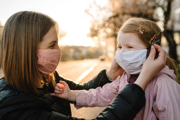 Coronavirus the end concept. No more covid-19. Little girl, mother wear masks walk on street. Mom removes mask happy child. Family with kid outdoors. celebrating success. Pandemic is over, has ended. - 写真・画像