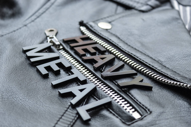 Primer plano de una palabra de letras negras HEAVY METAL sobre una chaqueta de cuero motero negro. Amantes de la música heavy metal y el estilo concepto de moda
 - Foto, Imagen