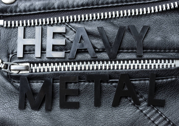 Closeup to a HEAVY METAL black lettering word over a black biker leather jacket. Heavy metal music lovers and fashion concept style - Photo, Image