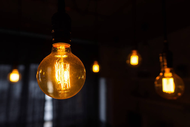 Close-up of incandescent light bulbs hanging in the dark room. Inefficient filament light bulbs waste electricity. Decorative antique edison light bulbs with straight wire. Dimmable, warm white, E27 - Photo, Image