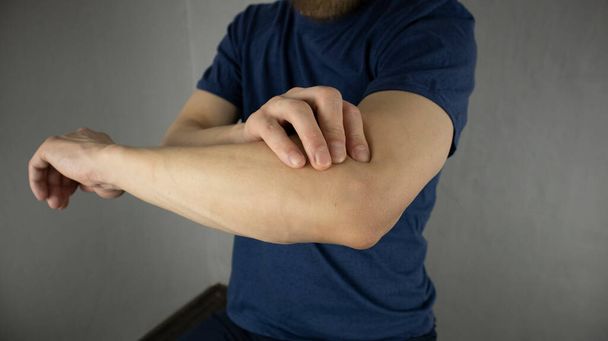 ein Mann macht eine Selbstmassage des Ellbogengelenks - Foto, Bild