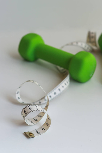 preparing the body for summer in sports. green dumbbells and centimeter - Valokuva, kuva