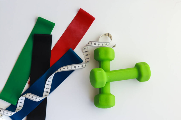 preparing the body for summer in sports. green dumbbells and a centimeter in a plane on top - Foto, Imagen