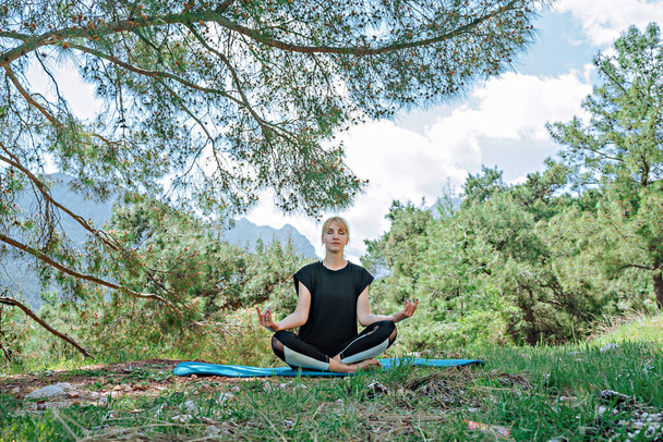 Femme faisant des poses de yoga à l'extérieur et belle vue sur les montagnes et la forêt
 - Photo, image