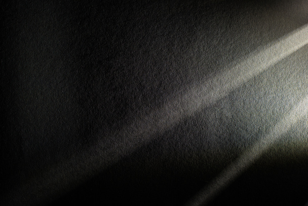 lekki pryzmat z belkami na ciemnym, teksturowanym tle - Zdjęcie, obraz