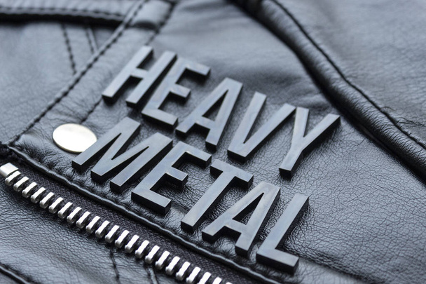 Blízko černého nápisu HEAVY METAL na kožené bundě černého motorkáře. Heavy metal milovníci hudby a módní koncept styl - Fotografie, Obrázek