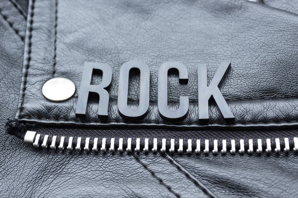 Primer plano de una palabra de letras ROCK negro sobre una chaqueta de cuero motorista negro. amantes de la música rock y el estilo concepto de moda
 - Foto, imagen