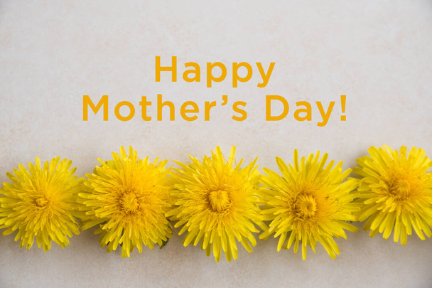 Happy Mothers Day. Yellow dandelions lies on a light textured surface. Wedding card. Flat lay, top view - Photo, Image