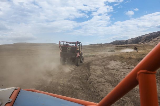 Buggy moves on a dirt dusty road in a mountainous area - Fotoğraf, Görsel