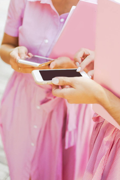 esküvő szervezők rózsaszín ruhák tartani rózsaszín tabletta és telefon - Fotó, kép