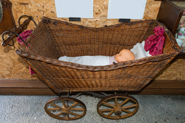 Close-up view on old infant cradle. Traditional cradle with toy of baby in the room. Old cradle on wheels - Photo, Image