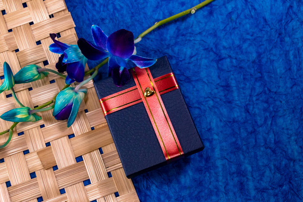 Vista dall'alto di una scatola regalo blu con fiori di orchidea su uno sfondo strutturato unico. Concetto regalo di matrimonio
 - Foto, immagini