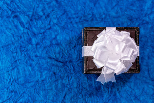 Вид зверху на коричневу подарункову коробку в ландшафтному режимі на синьому фоні. Концепція подарунків на річницю весілля
 - Фото, зображення