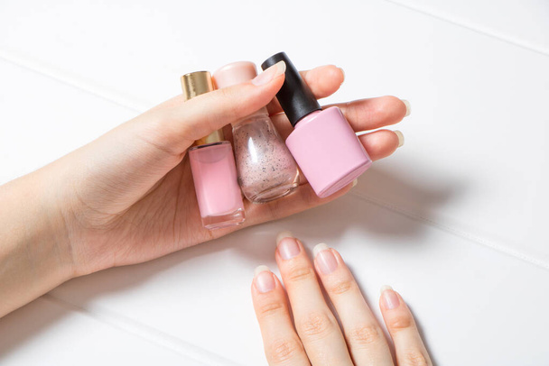 Manicure. A woman holds nail Polish. The girl chooses the color of the nail Polish. French, nail care. Nail salon, procedure, SPA. Home nail care. Manicure tools. Beauty, lifestyle, Glamour - 写真・画像
