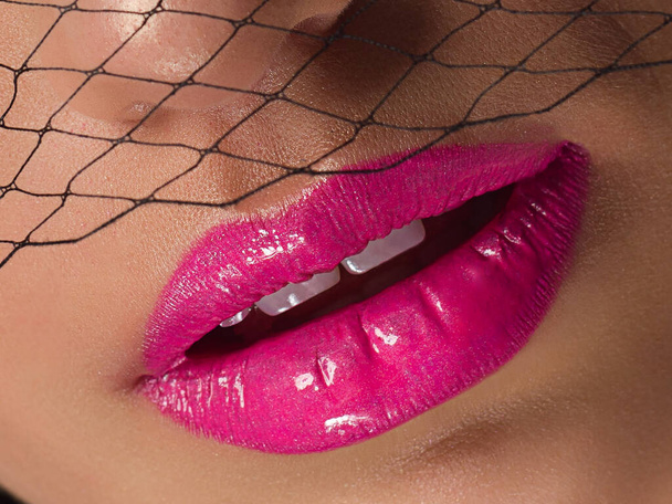 Cosmetics, makeup and trends. Bright lip gloss and lipstick on lips. Closeup of beautiful female mouth with pink lip makeup. Beautiful part of female face. Perfect clean skin in natural light - Φωτογραφία, εικόνα