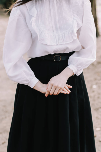 Student or college girl in uniform. Hands of the girl close-up. Girl wearing black skirt and white blouse - 写真・画像