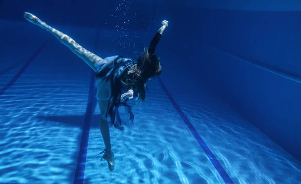 Ballerina jumps into the pool, slender professional dancer under the water and above the surface of the water, frozen movement dancing under the water in Pointe shoes - Фото, изображение