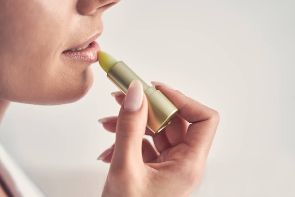 Young woman using a natural lip moisturizer - Foto, afbeelding