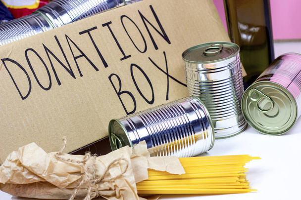 食品(パスタ、缶、豆など)と寄付カートンボックス。ボランティアや社会的支援、慈善の概念. - 写真・画像