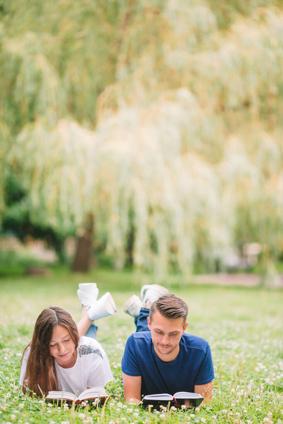 Young romantic couple lying in park and reading books - Photo, image