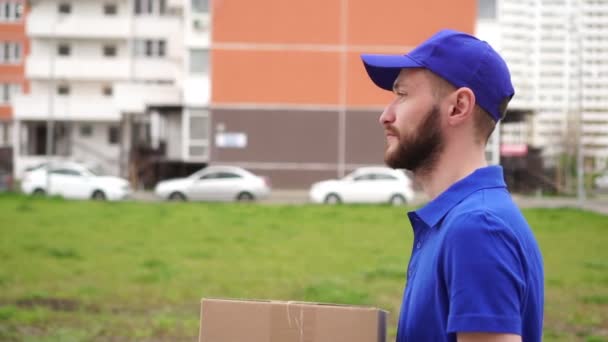 Male delivery man. Man courier carries a cardboard box. Postman deliveryman - Footage, Video