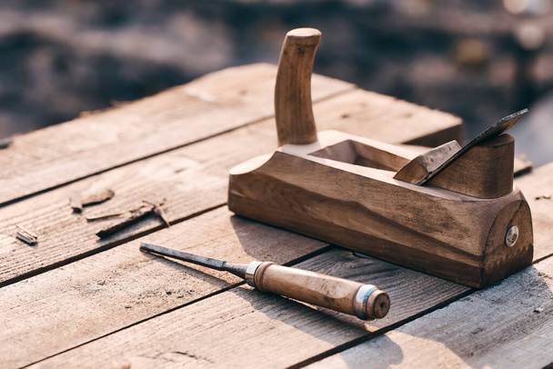 wooden background. Jointer plane and chisel lies on the village table along with sawdust. Wood thread tool. solar lighting. macro photo - Photo, Image