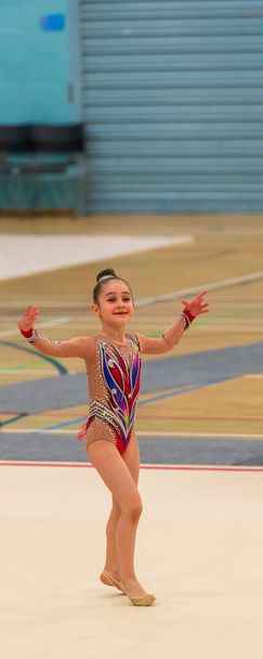 Genç bir jimnastikçinin portresi. 7 yaşındaki bir kızın ritmik jimnastik yarışmalarındaki portresi - Fotoğraf, Görsel