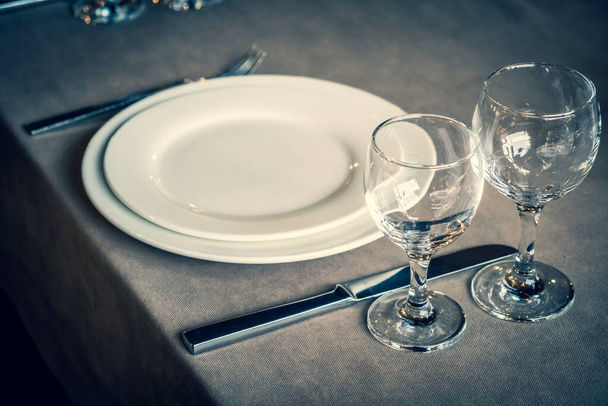 The served table in the restaurant. Clean dishes and appliances on the tablecloth in a cafe. Shiny transparent glasses. White plates. Prepared for the reception of guests. High service. - Fotó, kép