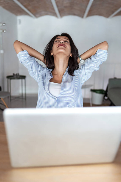 Laukaus väsynyt nuori liiketoiminnan nainen ottaa hetken rentoutua työskennellessään hänen kannettava tietokone toimistossa
. - Valokuva, kuva