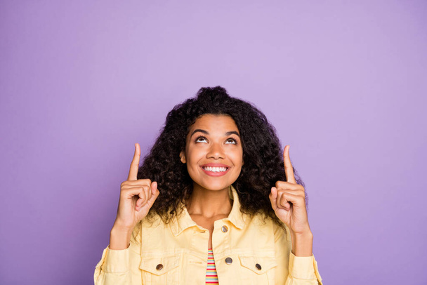 Portrait of positive cheerful afro american girl promoter point index finger copyspace recommend suggest promo ads wear casual style outfit isolated over violet color background - Foto, immagini