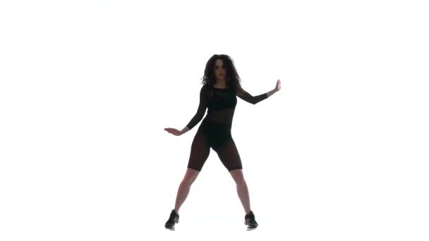 fiatal gyönyörű lány egy fekete átlátszó szűk öltöny energikusan táncoló táncol, street dance, twerk ellen fehér háttér, elszigetelt  - Felvétel, videó
