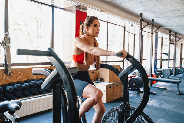 Confident young attractive sportswoman exercising on an elliptical machine at the gym - Fotografie, Obrázek