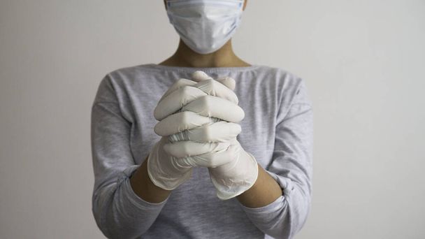Woman with a surgical mask and white medical gloves praying. - Foto, Imagem