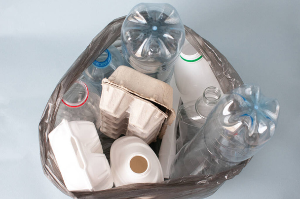 plastic, sorted garbage lies in a bag on a light background, white bottles, paper, glass. concept of ecology, sorting garbage . - Valokuva, kuva