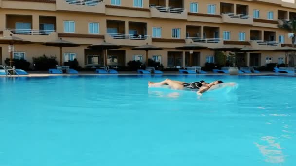 A drone flying over a pool in Egypt where a girl is lying on a mattress - Záběry, video