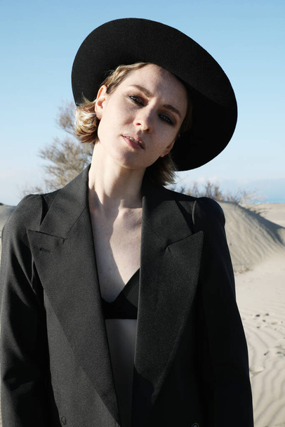 Fashion portrait of young elegant woman outdoor. Black coat, fedora hat. Vertical. - Foto, Imagem