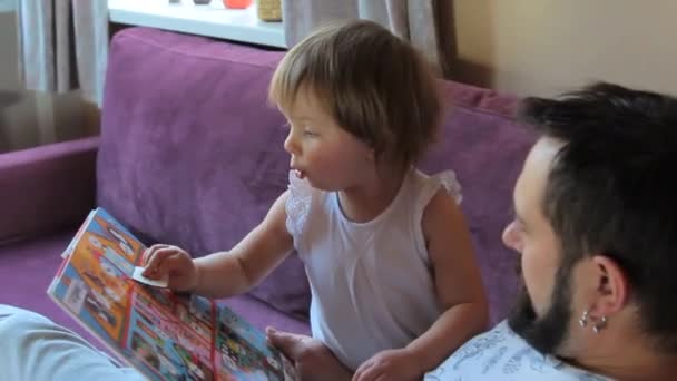 Father is reading a book with his little todler daughter at home - Footage, Video