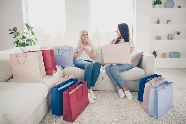 Portrait of positive cheerful retired woman sit cozy couch on floor many shopping bags her daughter give present for 8-march leisure celebration in room house indoors - Φωτογραφία, εικόνα