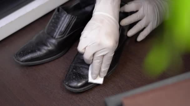 4k hand het dragen van witte beschermende handschoen vegen zwarte lederen mannelijke schoenen, mee naar huis bacteriën, desinfecterende veeg, zorg, corona virus covid-19 verspreiding, het doden van kiemen, gezondheidszorg, desinfecterende doekjes - Video