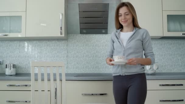 Pretty Caucasian young woman in pajama standing in the sunny kitchen in the morning, drinking hot coffe or tea and enjoying her time. Stay at home, quarantine, pandemic, coronavirus ,virus - Footage, Video