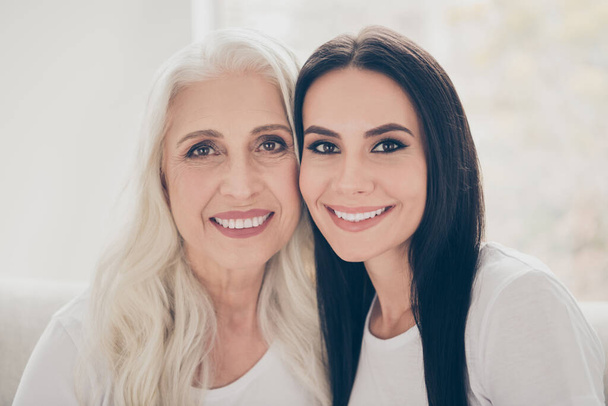 Close-up portrait of two nice attractive lovely tender cheerful women mom mommy adult daughter spending time day together in white light interior house flat apartment indoors - Φωτογραφία, εικόνα