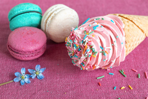 Macaroons brancos, azuis e roxos, cone de waffle com marshmallow caseiro e flor de primavera em um guardanapo de linho. Macarons ou macaroons é uma sobremesa francesa ou italiana. Close-up
 - Foto, Imagem