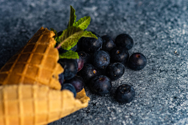 Organic blueberry fruits in waffle cone on concrete background with copy space - Photo, Image